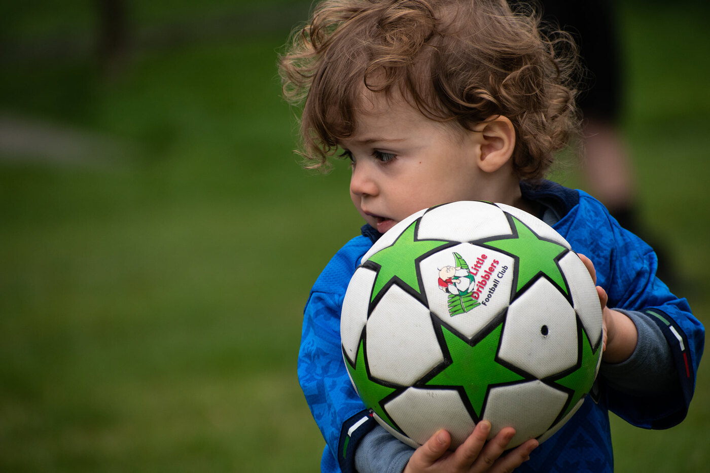 A Little Dribbler holding a branded green-star football